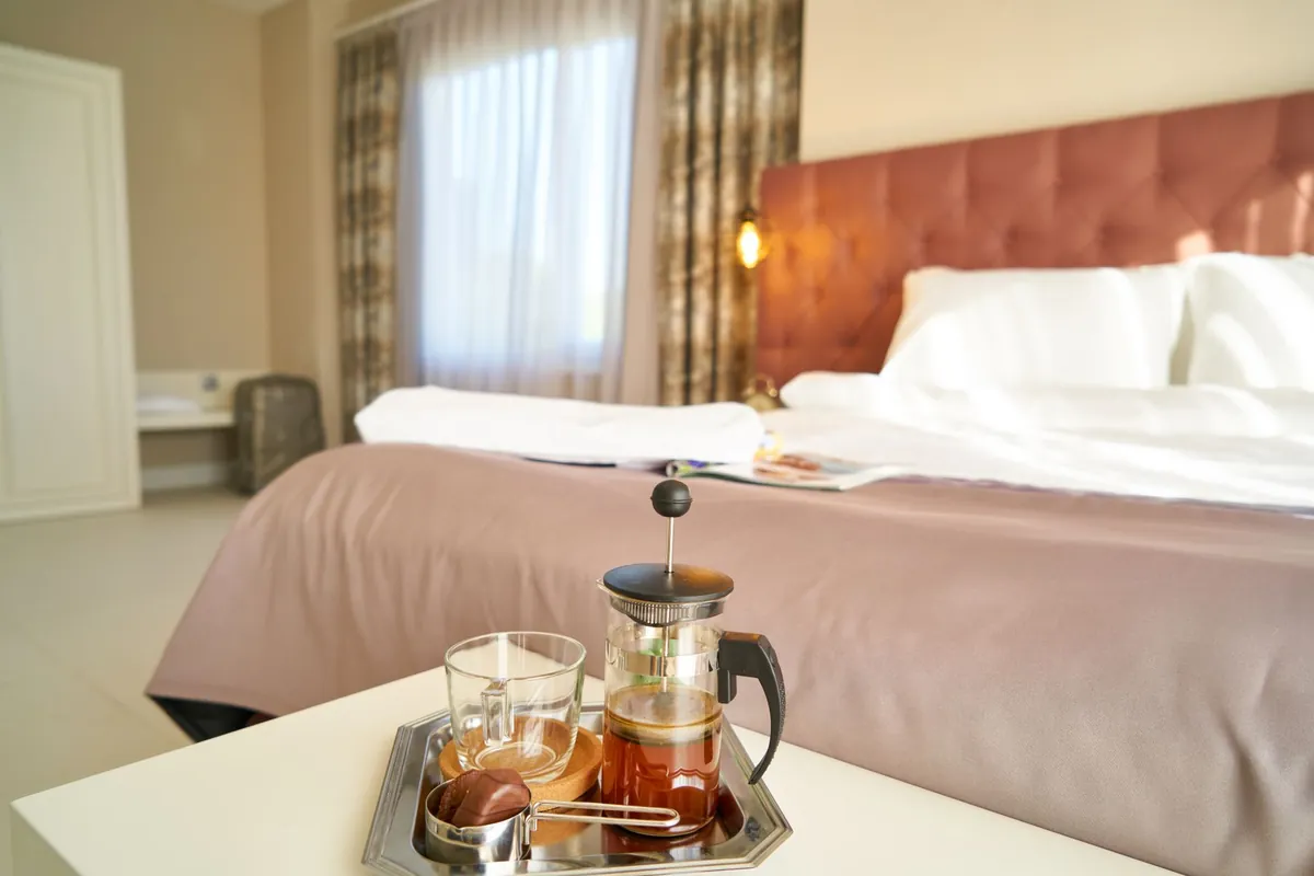 Guesthouse room with the bed made and a breakfast tray with a cafetière on the table in the foreground
