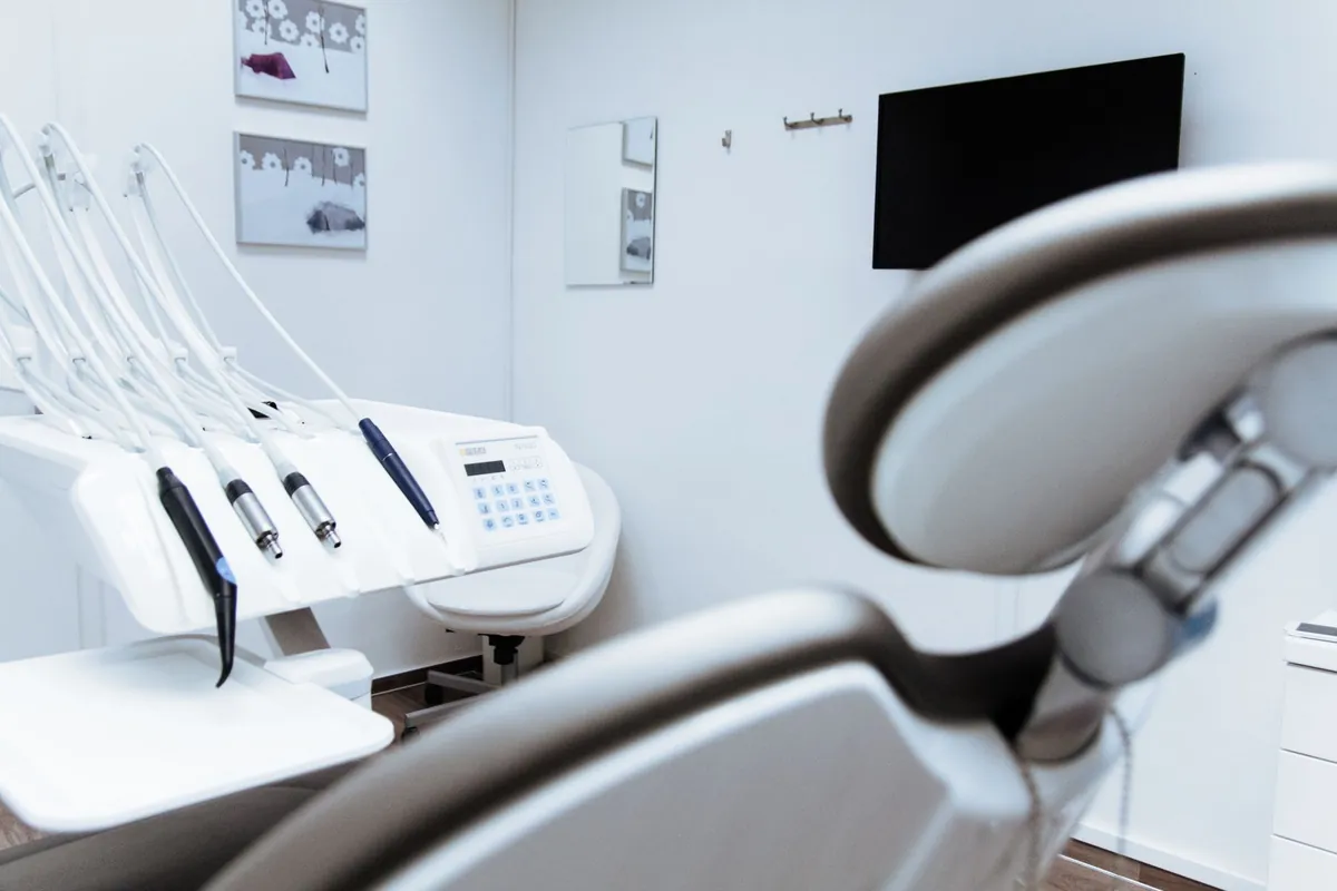 Dental surgery with the reclined chair, the handpieces hanging on the delivery unit and a screen switched off on the wall facing the patient