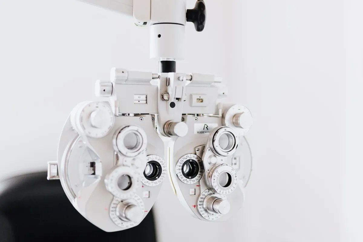 Foróptero branco de um consultório de oftalmologia, com os discos de lentes e as escalas numéricas, sobre parede clara