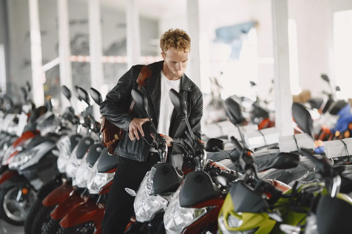 Verkaufsraum eines Motorradhändlers mit Reihen neuer Maschinen noch in Folie und einem Kunden, der eine ansieht