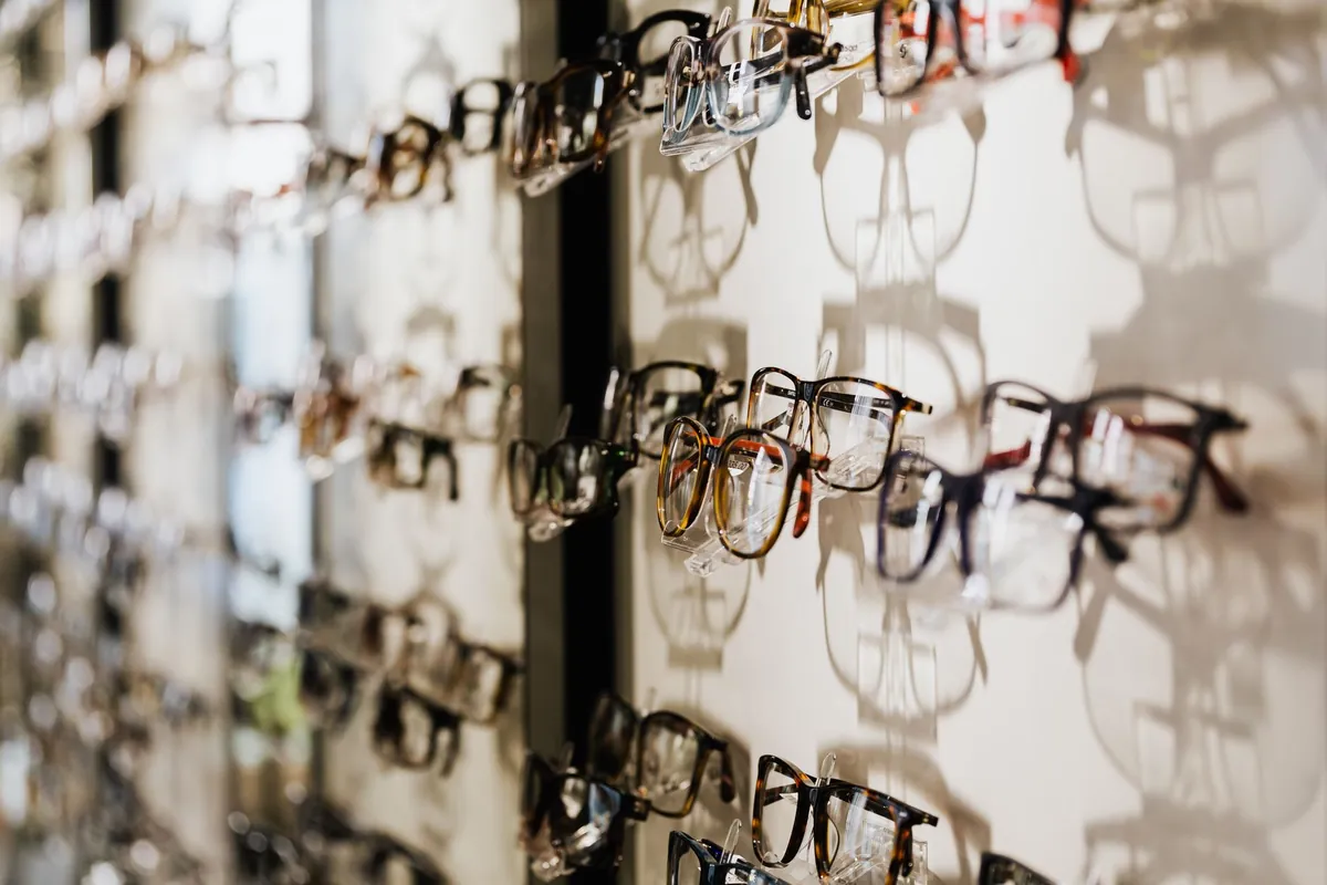 Präsentationswand eines Optikers mit reihenweise aufgehängten Fassungen und ihren Schatten auf der weißen Platte